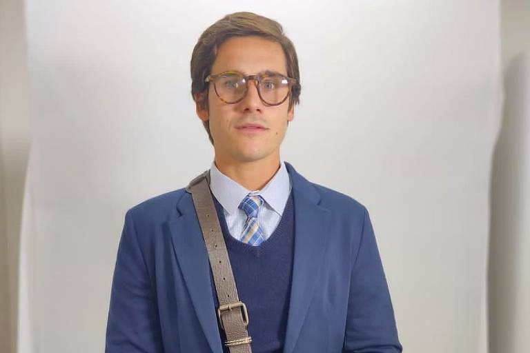 Em foto colorida, homem de terno gravata posa em um estúdio