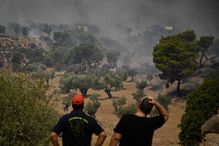 Bombeiro e morador local observam incêndio perto de Nea Peramos, a oeste de Atenas, na Grécia