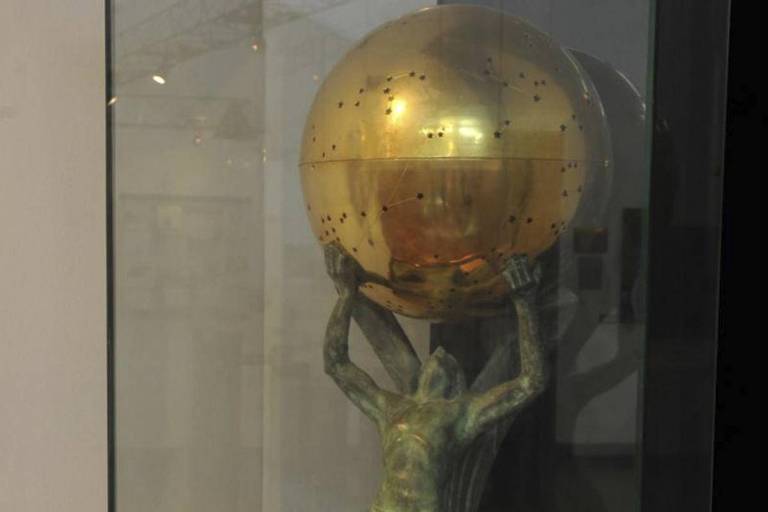 Estátua de um homem segura um globo metálico dourado, onde está guardado o coração de Santos Dumont