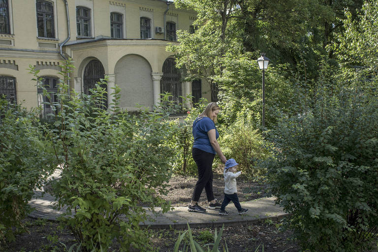 Anna Kolesnikova leva seu filho Mikola Kolesnikov para passear do lado de fora de hospital infantil em Kiev