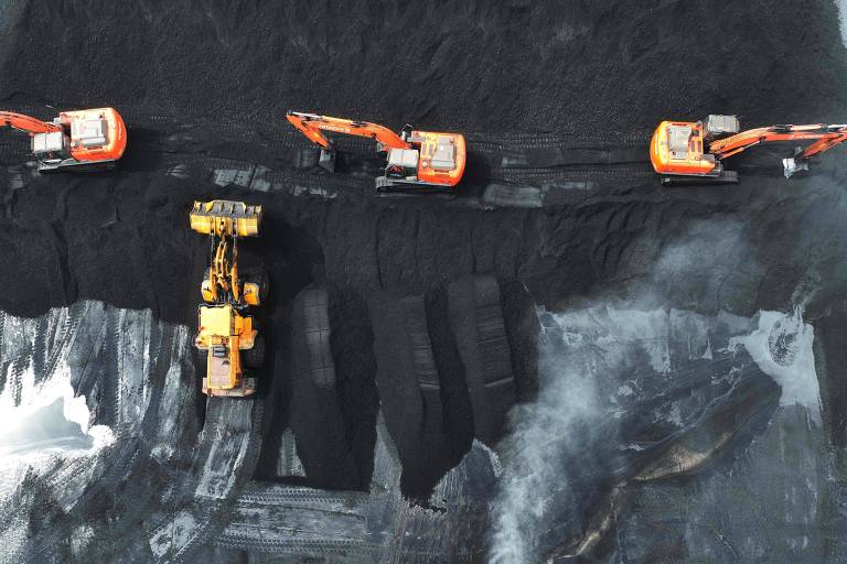 Vista aérea de escavadeiras alaranjadas e amarelas movendo carvão em porto 