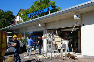 Workers remove rubble after an ATM cash dispenser was blown upon at a local bank in Bad Vilbel