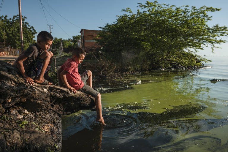 Luis Javier e Luis David brincam nas margens do lago Maracaibo, que tem água poluída por vazamentos da indústria petrolífera
