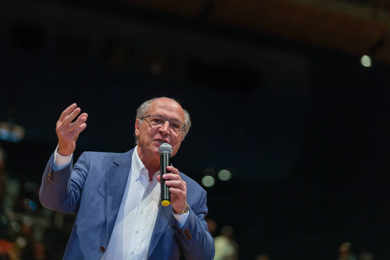 Geraldo Alckmin fala em plenária em São Paulo. Ele aparece da cintura para cima. Com camisa branca, terno azul e óculos de grau, ele gesticula com a mão direita e segura o microfone com a mão esquerda