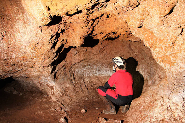 A foto mostra um pesquisador agachado dentro de paleotoca encontrada na Grande Belo Horizonte em 2010.