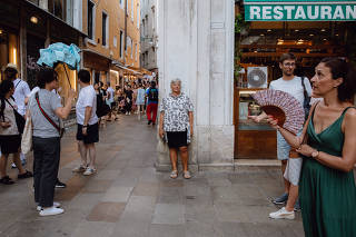 Monica Poli looks at people passing by in a crowded pedestrian area of Venice, Italy, July 16, 2023. (Matteo de Mayda/The New York Times)
