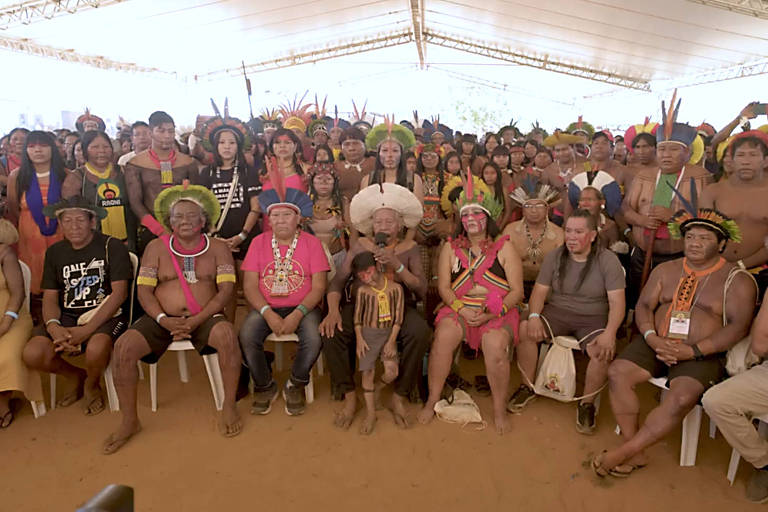 Dezenas de indígenas sentados em cadeiras num pátio coberto por lona no Xingu (MT)