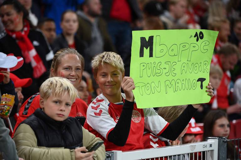 Em jogo em Copenhague entre as seleções da Dinamarca e da França, menino mostra cartaz no qual pede ao francês Mbappé que lhe presenteie com a camisa