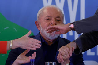 O presidente Lula (PT) cumprimenta colegas de mesa durante evento em Brasília