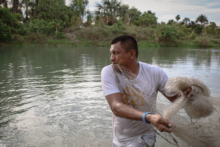 Homem joga rede de pesca em um rio