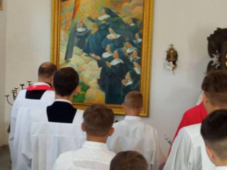 Religiosos se reúnem para fazer uma oração diante de uma pintura que homenageia 11 freiras mortas por nazistas durante a Segunda Guerra Mundial