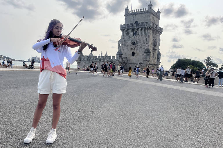A estudante Andressa Lélis, 15, toca viola em frente à Torre de Belém, em Lisboa, onde se apresentou com a Orquestra Maré do Amanhã