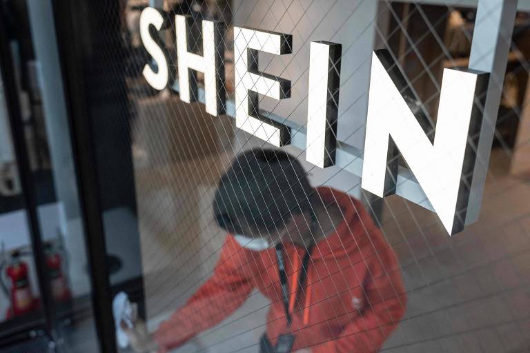 Imagem mostra um homem limpando as vitrines de uma sala de exposição da Shein durante evento da plataforma chinesa em Tóquio, no Japão