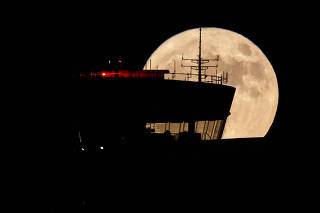 A supermoon, also known as a Sturgeon moon is seen behind an air traffic control tower at Ben Gurion International Airport at Lod, near Tel Aviv