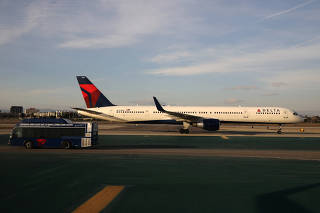 FILE PHOTO: A Delta plane passes a Delta bus on the tarmac at LAX airport in Los Angeles