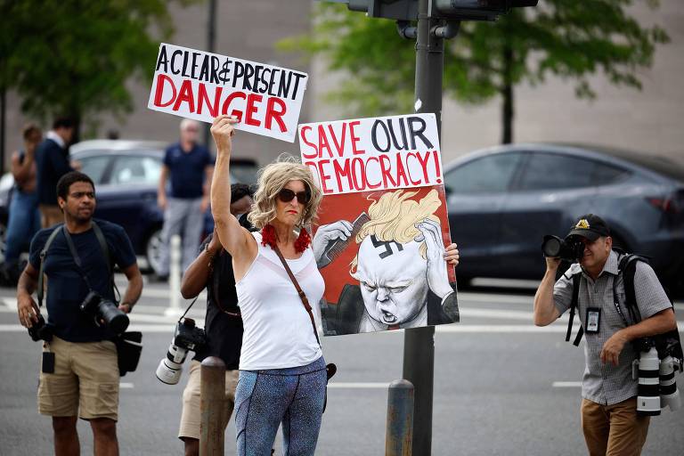 Manifestante contra o ex-presidente Donald Trump protesta em frente ao tribunal no qual o republicano se apresentou à Justiça, em Washington
