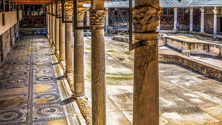 Imagem de uma casa romana, toda feita de mármore, com amplo salão central e corredores ao lado, separados por pilares