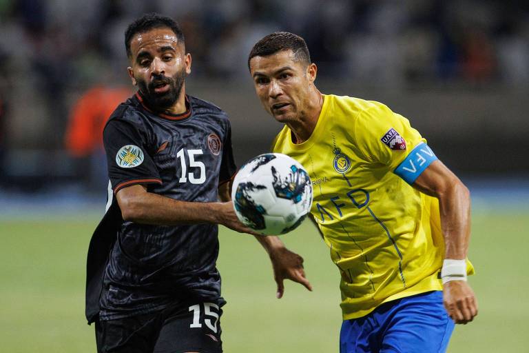 Jogador do Al-Nassr, Cristiano Ronaldo, usando camisa amarela, disputa a bola com Hussain al-Qahtani, do Al-Shabab pela Liga dos Campeões Árabes