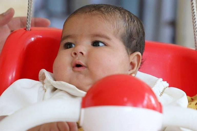 Bebê Afraa em um balanço vermelho
