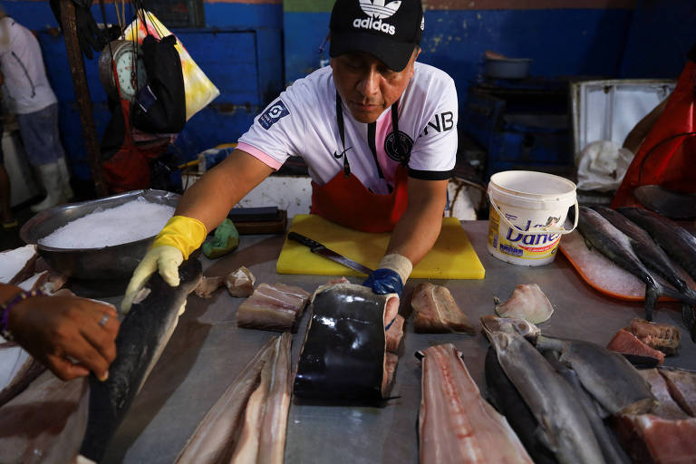Homem vende carne de tubarão em feira de peixes em Tumbes, no Peru