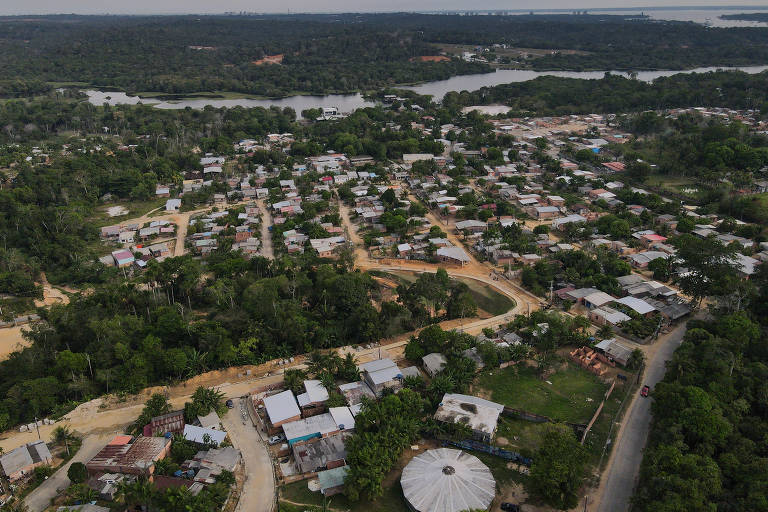 foto aérea de cidade cercada de floresta e cortada por rios, com pequenas edificações