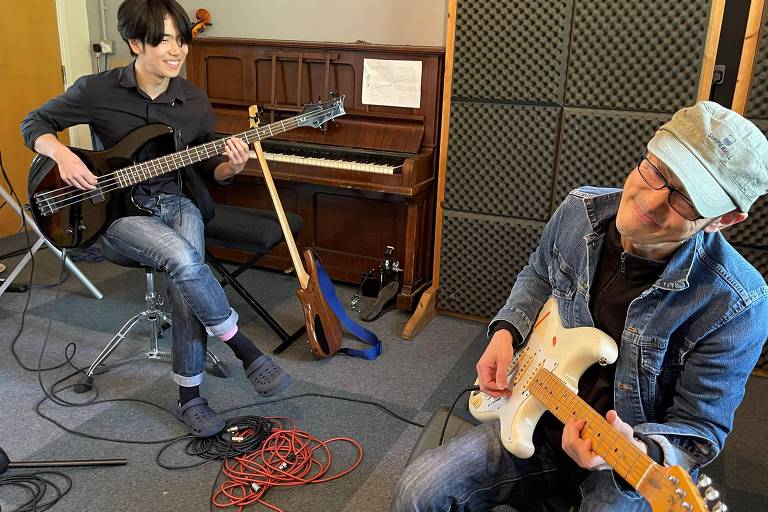 Pai e filho tocam guitarra e baixo em estúdio