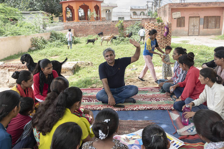 Sunil Jaglan fala sobre saúde com mulheres em uma vila agrícola no estado de Haryana; todos estão sentados no chão