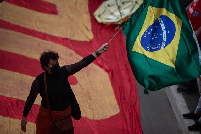 Mulher contra a luz segura bandeira do Brasil sob fundo vermelho à esquerda