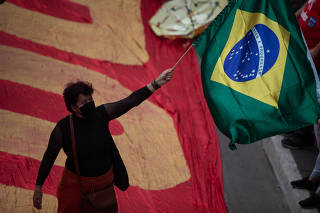 Manifestante com bandeira durante protesto organizado pela esquerda na av. Paulista