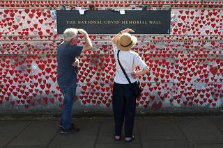 People view messages written on the National Covid Memorial Wall, in London