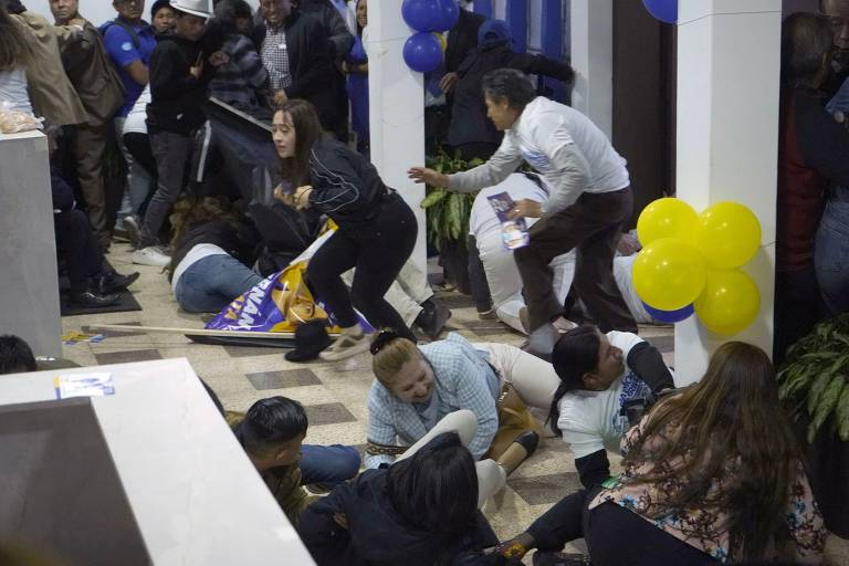 Pessoas tentam se proteger de tiros no local em que o candidato à Presidência do Equador Fernando Villavicencio foi morto, em Quito