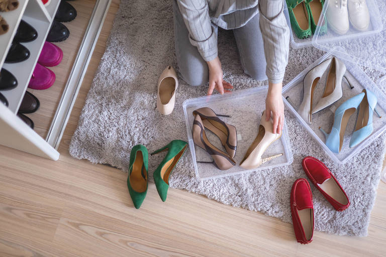 Mãos femininas embalam sapatos nos calcanhares em caixa de plástico guarda-roupa em casa método de armazenamento organização vista superior closeup. Mulher dona de casa durante a limpeza geral, muitos calçados embalando cuidadosamente o armário
