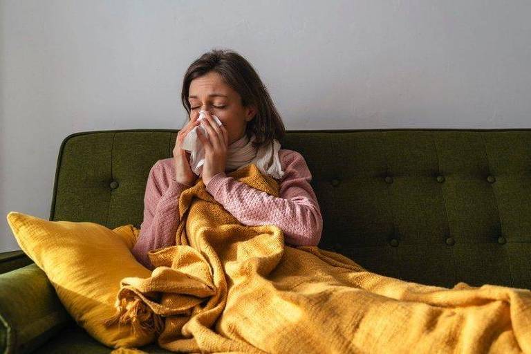 Mulher no sofá com sintomas de resfriado