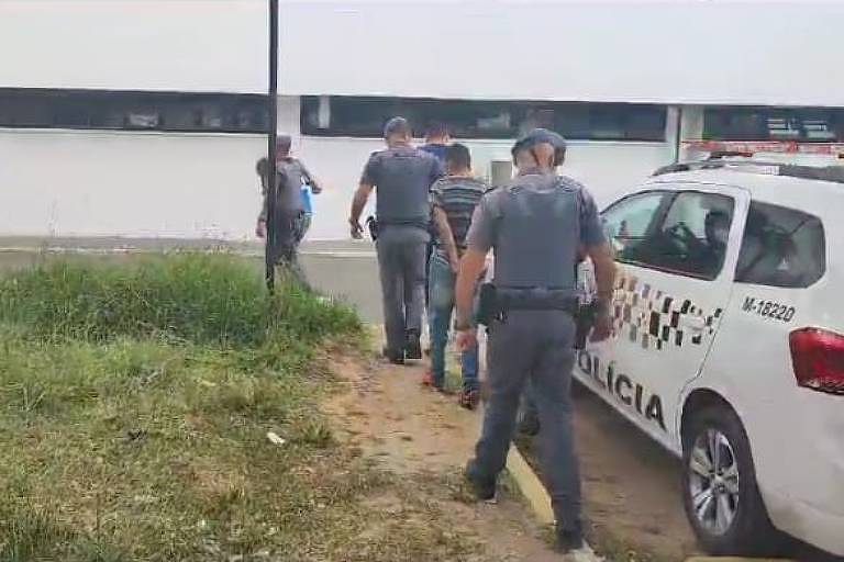 Policiais militares conduzem três homens detidos para a delegacia