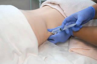 Doctor makes injection of ozone gas in patient abdomen on side on ozone therapy.