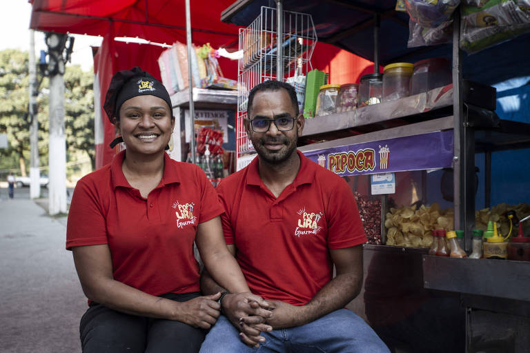 mulher e homem de camiseta vermelha diante de carrinho de comida de rua