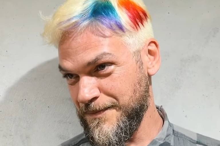Em foto colorida, homem mostra novo visual com cabelo platinado e mechas coloridas