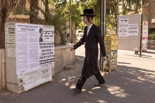 An ultra-orthodox man passing a sign that reads 