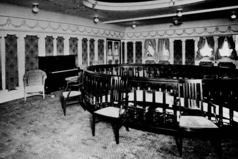 Foto em preto e branco mostra salão de música dentro de navio