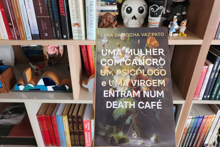 Capa do livro "Uma mulher com cancro, um psicólogo e uma virgem entram num death café", com a biblioteca da Cynthia ao fundo