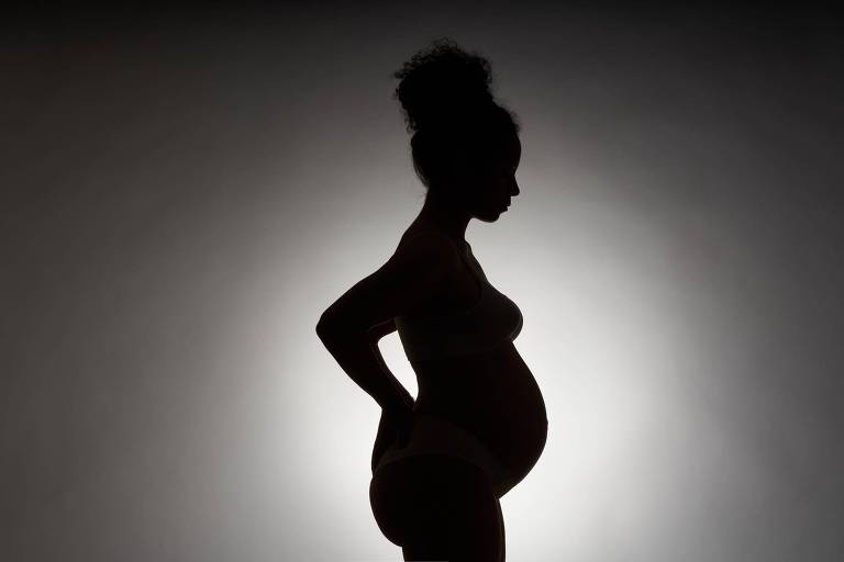 Mulher grávida é fotografada conta a luz, aparecendo apenas seu contorno