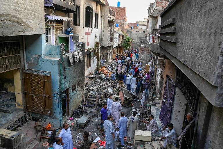 Policiais e residentes em meio a destroços ao lado de igreja em Jarawanla, distrito da cidade de Faisalabad, no leste do Paquistão