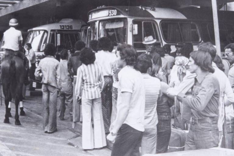Pessoas aguardando ônibus ao lado de plataformas na rodoviária da Luz, em 1976