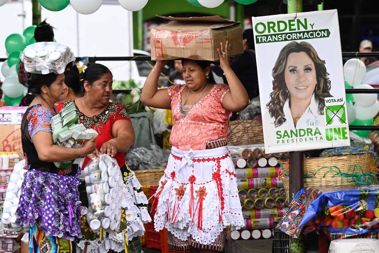 Vendedoras ambulantes ao lado de cartaz da candidata Sandra Torres, na Cidade da Guatemala