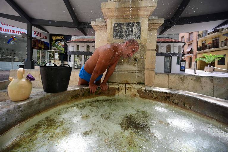 Homem se refresca em fonte na cidade de Valência, na Espanha, em dia que superou 44°C