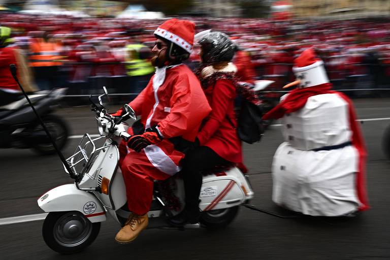 Homem fantasiado de Papai Noel anda de Vespa durante evento natalino em Turim, na Itália