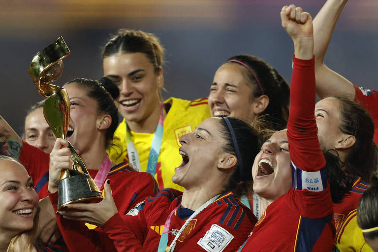 JOgadoras da seleção espanhola, com o troféu na mão, comemoram o título da Copa do MUndo feminina sobre a seleção da Inglaterra