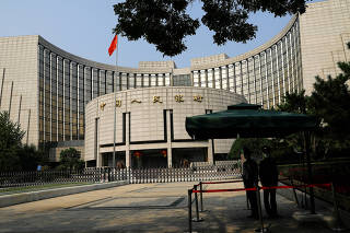 FILE PHOTO: Paramilitary police officers stand guard in front of the headquarters of PBOC in Beijing