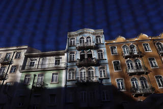 Residential buildings are seen through a fence in Lisbon