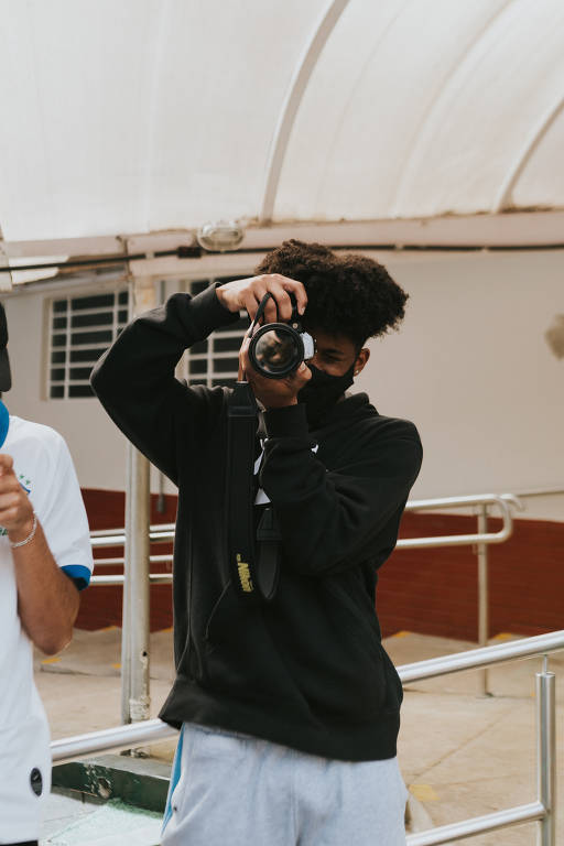 Jovem negro segura câmera fotográfica